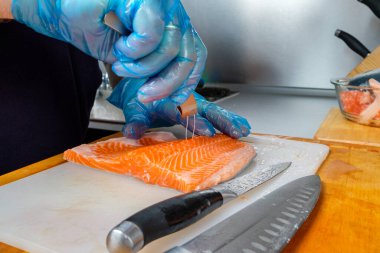 The chef uses special fish tweezers to remove bones from salmon fillets. clipart