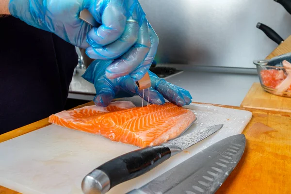 Шеф-кухар використовує спеціальні рибні пінцети для видалення кісток з філе лосося . — стокове фото