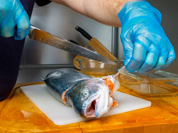 Рукавички кухаря відрізали плавці лосося ножем . — стокове фото