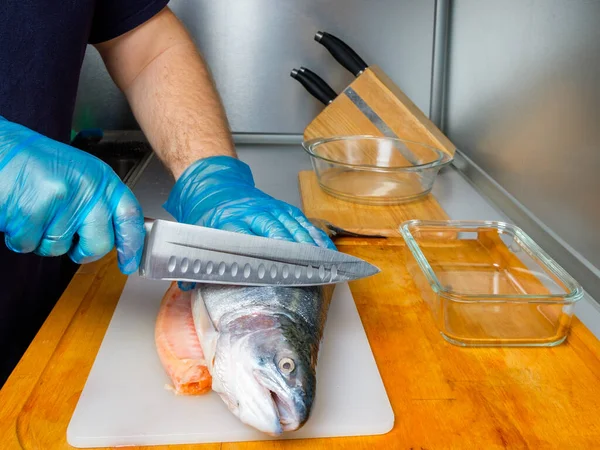 Руки кухаря в рукавичках розрізали тіло лосося ножем . — стокове фото