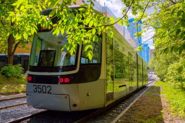 Şehir parkından modern bir tramvay geçiyor..
