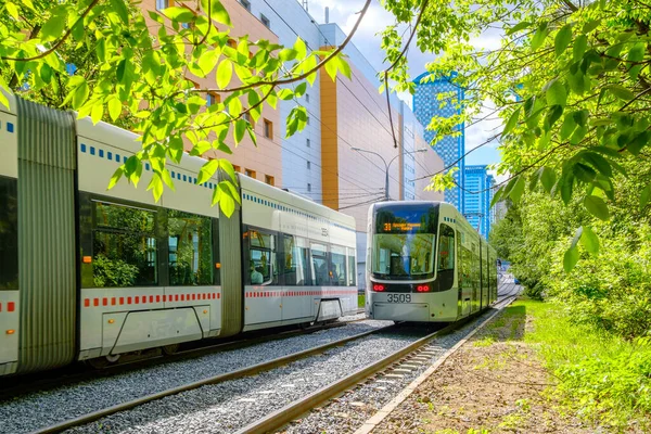 A modern tram runs through the city park. — Stock Photo, Image