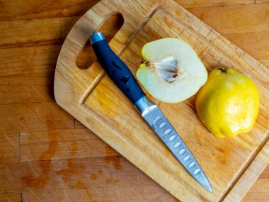 Dilimlenmiş ayva ve su damlaları olan bir bıçak tahta kesme tahtasına..