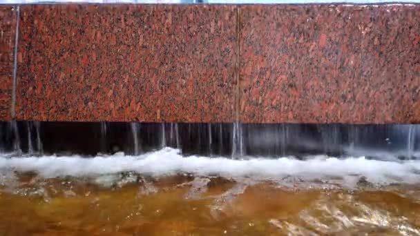 在温暖的阳光明媚的日子里，从泉水中喷出的水从花岗岩板上流下来 — 图库视频影像