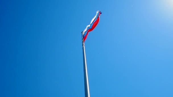 La bandera rusa ondeando en el viento contra el cielo azul sin nubes. — Vídeo de stock