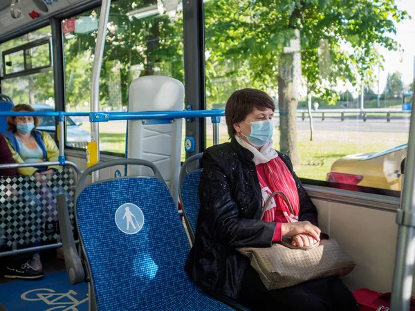 Взрослая женщина в защитной маске сидит у окна в городском автобусе — стоковое фото