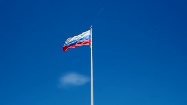 La bandera rusa ondeando en el viento contra el cielo azul sin nubes. — Vídeo de stock