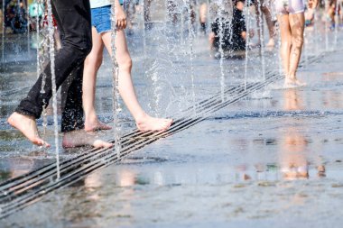 Güneşli bir yaz gününde, su püskürten çıplak ayaklı bir kadına odaklan..