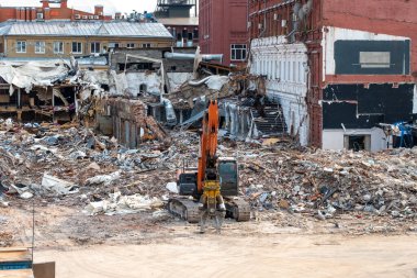 Yıkılmış bir binanın enkazının önünde bir kazıcı. 