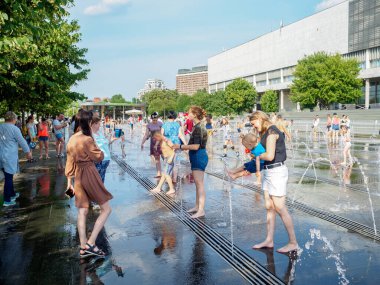 Yetişkinler ve çocuklar Muzeon Park 'taki fıskiyenin fıskiyesinde banyo yapıyorlar..
