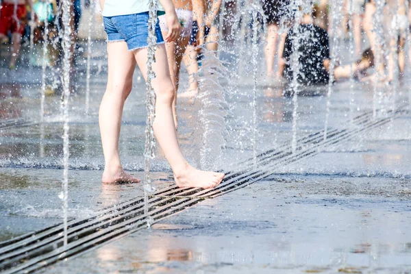 Feet of a woman barefoot in the spray of jets of water from the fountain. — Stock Photo, Image