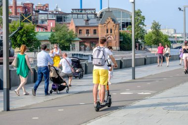  Bir adam ve bir çocuk bisiklet yolunda elektrikli scooter kullanıyor.