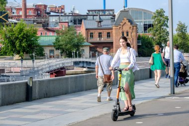 Genç kız güneşli yaz gününde elektrikli scooter kullanıyor.