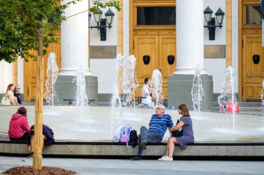 Güneşli bir yaz gününde, yetişkin bir çift çeşmede oturur..
