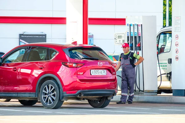 Ein Tankwart in Uniform betankt ein Auto an einer Tankstelle. — Stockfoto