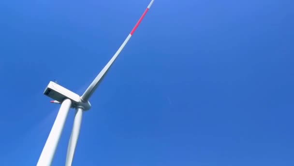 De bladen van de windturbine draaien tegen de blauwe wolkenloze lucht. — Stockvideo