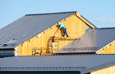 İşçiler bir kır evinin çatısını tamir ediyorlar..