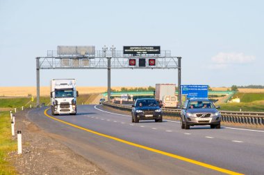 Yüksek hızda giden arabalarla asfalt köy yolunun manzarası.