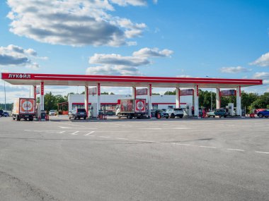 Güneşli bir yaz gününde Lukoil 'in kırmızı ve beyaz renklerinde bir benzin istasyonu.