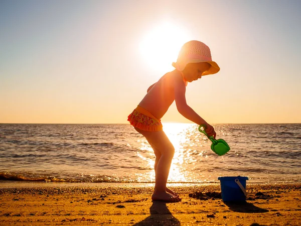 Anak bermain di pasir oleh laut saat matahari terbenam — Stok Foto
