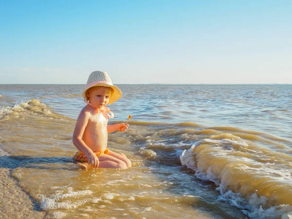 Anak gadis duduk di air laut di pantai. — Stok Foto