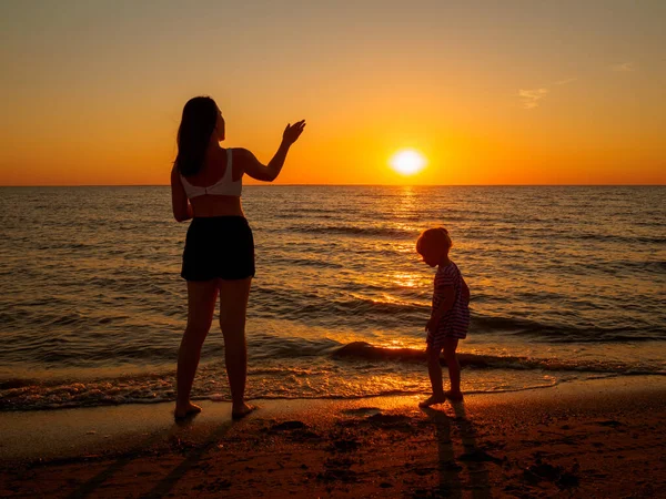 Jovem mulher e menina na praia ao pôr-do-sol. — Fotografia de Stock