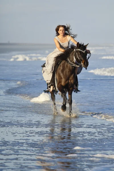 Woman riding horse through surf — Stock Photo, Image