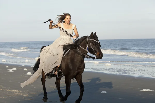 Kobieta na galopujący koń na plaży — Zdjęcie stockowe