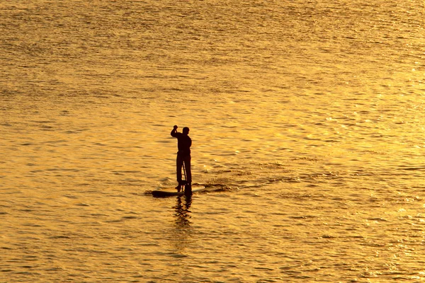 Silhouet van man paddleboarding — Stockfoto