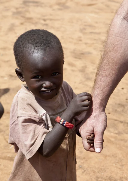 Criança africana segura mão de trabalhador humanitário — Fotografia de Stock