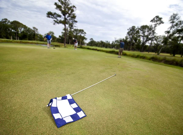 Флаг и игроки в гольф — стоковое фото