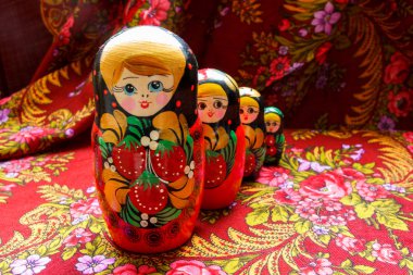Four nesting dolls of various sizes on a red floral background