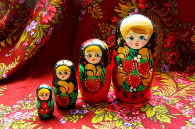 Four nesting dolls of various sizes on a red floral background