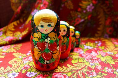 Four nesting dolls of various sizes on a red floral background