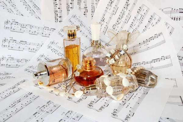 Vials of perfume and toilet waters surrounded by jewelry and music
