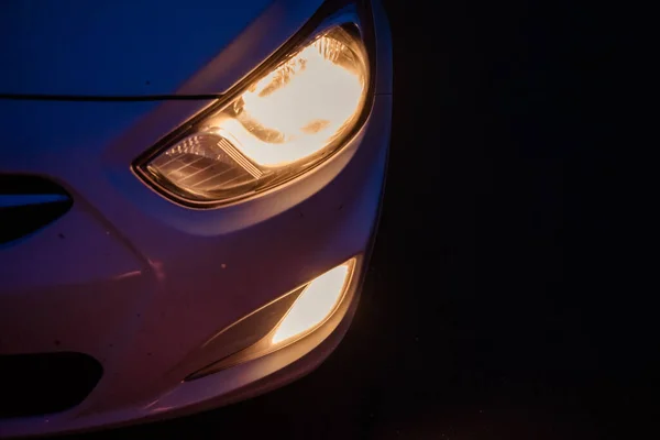 Headlights of a white car at dusk — Stock Photo, Image