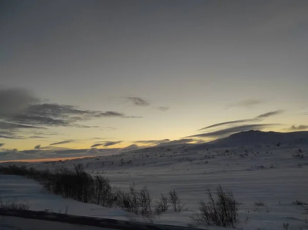 the land is covered with white snow and the sun is dawn in the Murmansk region