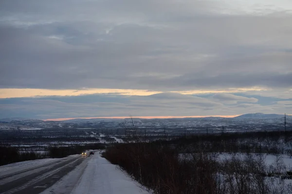 Amanhecer em uma estrada de inverno com nuvens — Fotografia de Stock