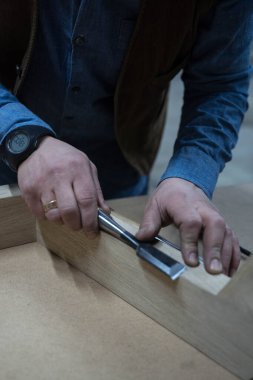 Bir adam özel bir aletle tahta bir tahta yerleştirir.