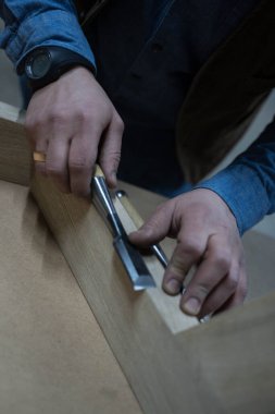 Bir adam özel bir aletle tahta bir tahta yerleştirir.