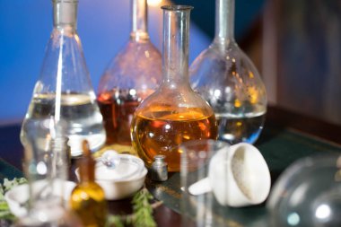 Masanın üzerinde farklı boyutlarda cam mataralar ve sıvı kavanozları var.