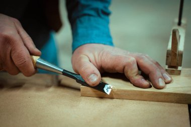 Bir adam mobilya yapıyor, aletlerle detayları kesiyor.