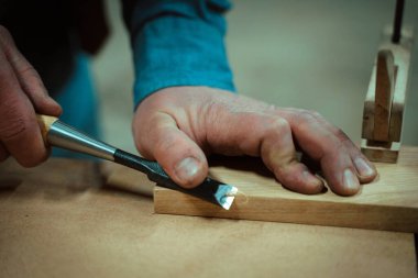 Bir adam mobilya yapıyor, aletlerle detayları kesiyor.