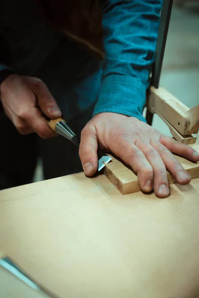 a man makes furniture, cutting details with tools