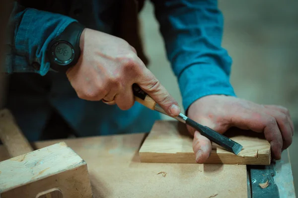 a man makes furniture, cutting details with tools