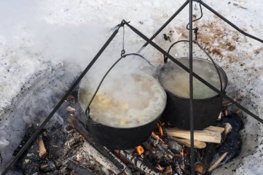 Ateşin üzerinde çorba standı olan iki dökme demir kap.