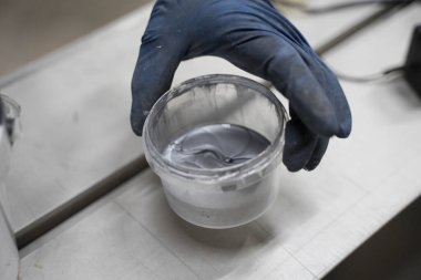 Bir adam mavi eldivenle boyayı yayar.