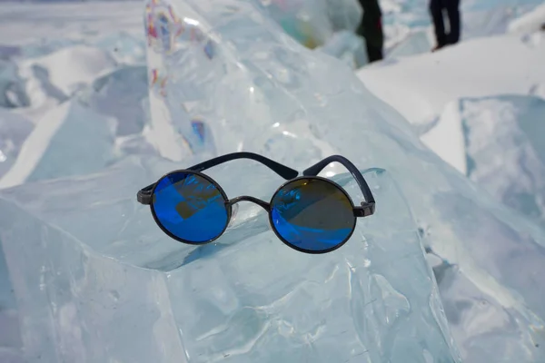 蓝色的太阳镜在阳光下放在冰上 — 图库照片