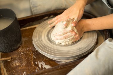 Kadın elleri çömlekçi çarkındaki çamurdan yemek yapar.