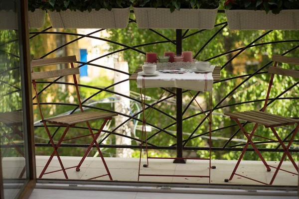 Balkon se dvěma židlemi, stolem a červenými květy — Stock fotografie